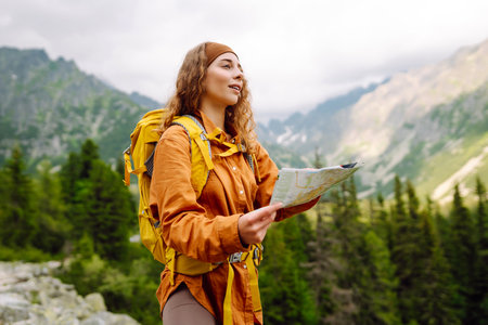 Woman traveler holds a map, explores hiking trails in the mountains. Hiking and adventure concept