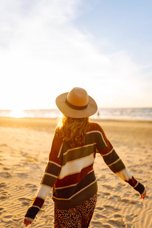 Beautiful curly woman on beach in cold sunny weather, deeply breathing fresh ocean breeze. Lifestyleの写真素材