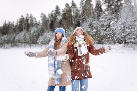 Two young females in warm clothes and scarfs. Carefree women posing in the street in winter parkの写真素材