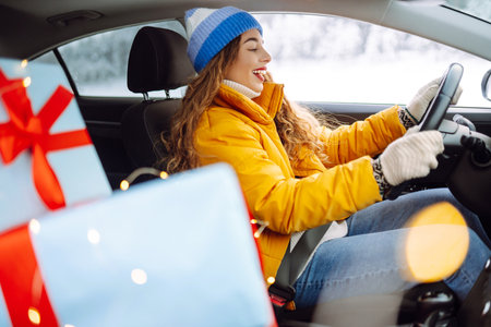 A beautiful woman driving a car carries New Year's gifts along a snowy road. Shopping concept.の写真素材