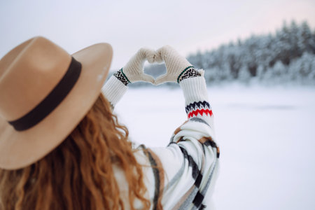 Women's hands in mittens symbolize a heart against the backdrop of a winter landscape. Lifestyleの写真素材