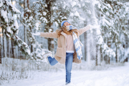Young woman in warm clothes plays with snow on a sunny winter day. Concept of walking, fun.の写真素材