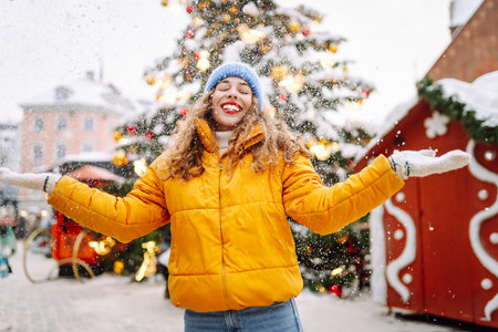 Young woman having fun with snow on a winter snowy day at the Christmas market. Fun, weekend concept.の写真素材