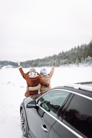 Two Happy woman near a car on a snowy road. Winter forest. Winter holidays. Journey for car.の写真素材
