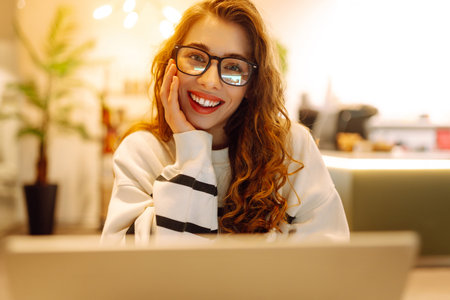 Young woman sitting on cafe with laptop. Beautiful college student on a cafe. Concept for educationの写真素材