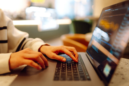 A young woman is engaged in typing on a laptop.