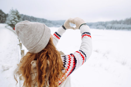 Women's hands in mittens symbolize a heart against the backdrop of a winter landscape. Lifestyleの写真素材