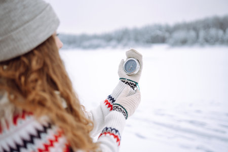 Close-up of a young woman in a hat holding a compass lying in her hand on a mitten.の写真素材