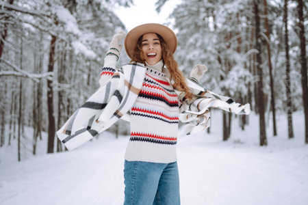 Young woman dressed in a sweater, scarf, hat posing in the winter forest.の写真素材