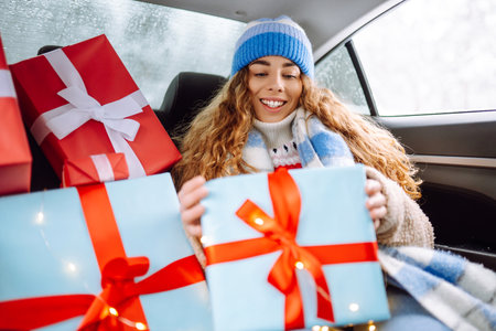 Beautiful young woman with New Year's gifts is riding in back seat of car. Concept of winter holiday