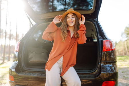 Happy woman enjoying nature while sitting in the trunk of her car during a solo trip. road trip