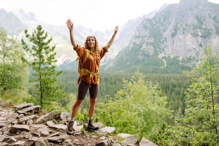 Young traveler woman with a yellow backpack on a cliff. Active lifestyle.の写真素材