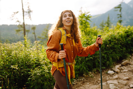 Young woman traveler hiking poles on trail among the mountains. Hiking. Active lifestyle.の写真素材