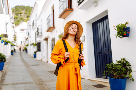 Young traveler woman in a vibrant orange dress and hat enjoys a sunny stroll. Concept of lifestyleの写真素材