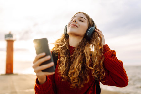 Relaxed woman enjoying music by the waterfront while wearing headphone. Travel and blogging conceptの写真素材