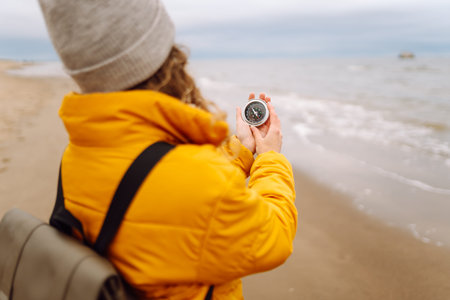 Woman traveler looking for directions with a compass on beach. Active lifestyle. Adventure concept.の写真素材