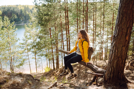 A cheerful young woman in a yellow jacket enjoying a sunny day by the lake. Active lifestyle.の写真素材