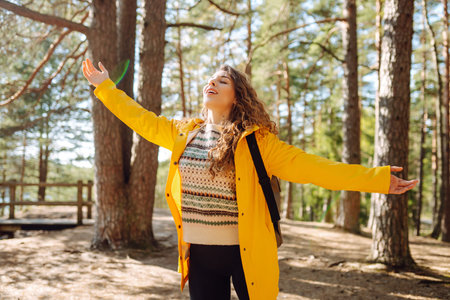 A cheerful young woman in a yellow jacket enjoying a sunny day by the lake. Active lifestyle.
