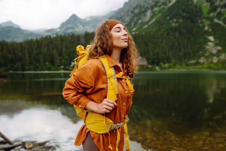 Hiker with a yellow backpack by an alpine lake