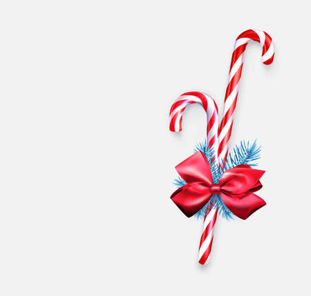 Two striped candy cane sticks with blue fir branch and red bow. Sale tag. Vector holiday illustration.のイラスト素材