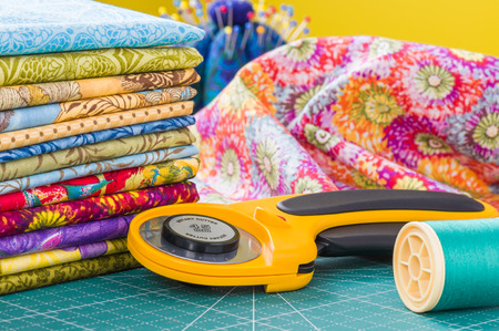 Rotary cutter and spool of thread on a background fabricの写真素材
