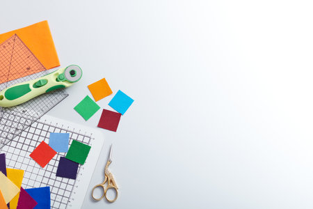 Bright square pieces of fabric, quilting and sewing tools, colored strips of fabric, space for textの写真素材