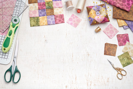 Bright square pieces of fabric, patchwork tools, sewing equipment, traditional quilting, space for...