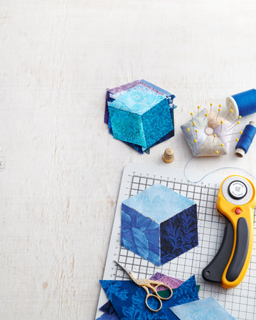 Preparation for sewing a cube from rhombuses, pile of stitched cubes, quilting accessories. Space...