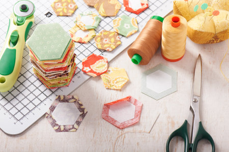 English paper pieced hexagons on white craft mat, sewing equipmentの写真素材