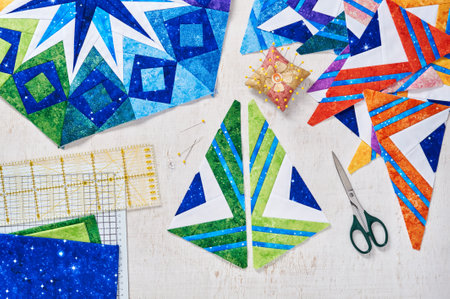 Fragments of quilt, accessories for patchwork, top view on a white wooden surface