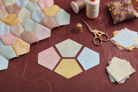 Preparation of pentagon pieces of fabric for sewing patchwork block, fragment of top of quilt and sewing accessoriesの写真素材
