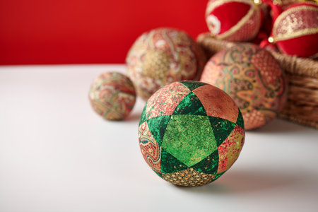 Patchwork puzzle balls and christmas decorations in basket on white and red backgroundの写真素材