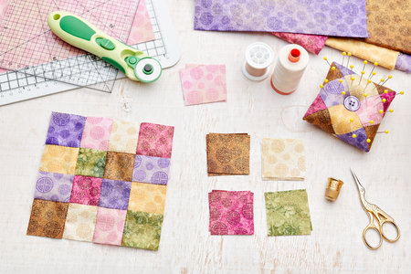 Bright square pieces of fabric, patchwork tools, sewing equipment, traditional quiltingの写真素材