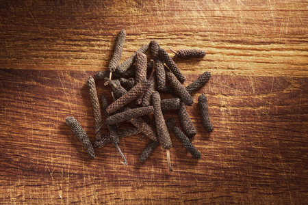 A heap of java long pepper on a wooden cutting boardの写真素材