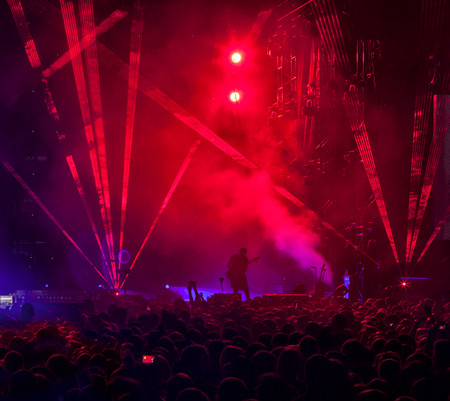 Silhouettes of a crowd of fans in front of bright scene lights.