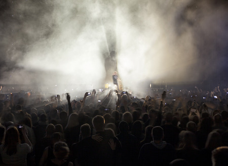 Silhouettes of a crowd of fans in front of bright scene lights.