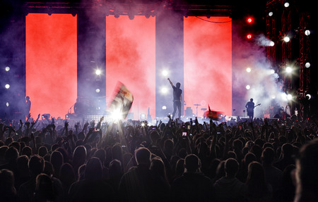 Silhouettes of a crowd of fans in front of bright scene lights.の写真素材