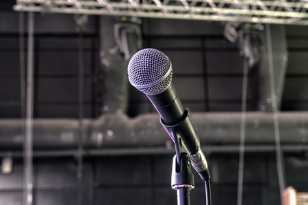 A dynamic microphone on stage. Bright spot light on the background.