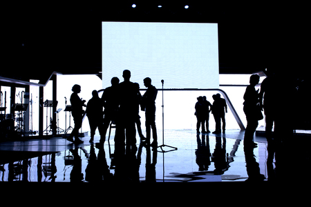 Silhouette of an people on the stage in the front of a colorful background.の写真素材