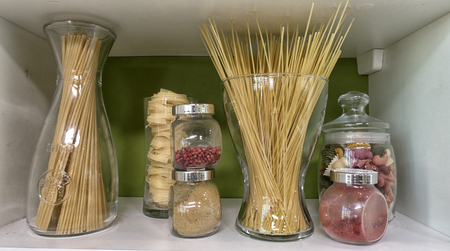 Various uncooked cereals, grains, beans and pasta for healthy cooking in glass jarsの写真素材