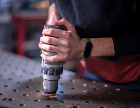 close up casual worker holding electric drill and repair furniture at homeの写真素材