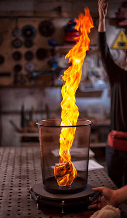 Gas burner made of brass with a flame escaping from it.の写真素材