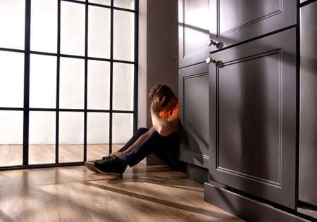 a man sitting on the floor with a phone behind a wardrobe