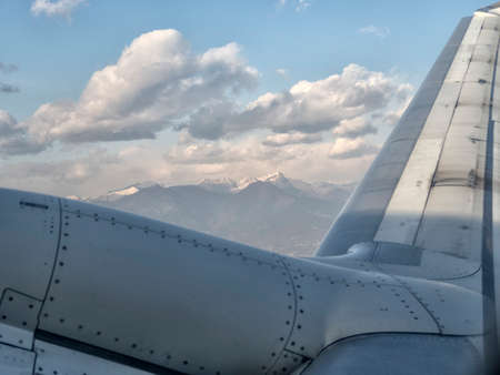 Aerial view of airplane wing and mountain peaks at European from above on airplane window.の写真素材