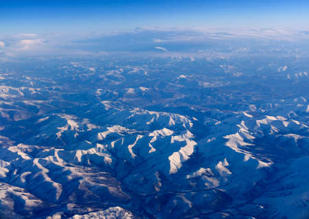 Aerial view of airplane wing and mountain peaks at European from above on airplane window.の写真素材