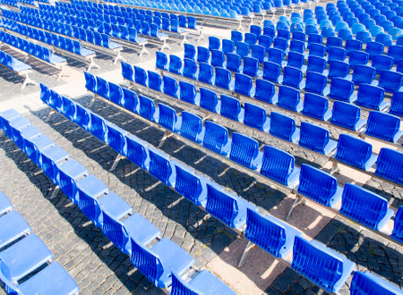 Blue chairs are placed on a row in an auditorium