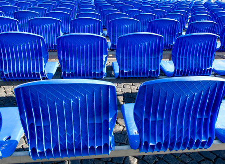 Blue chairs are placed on a row in an auditorium