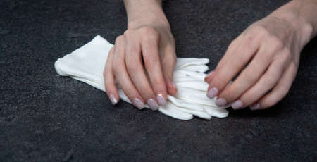 female hands in white cloth gloves on a dark background