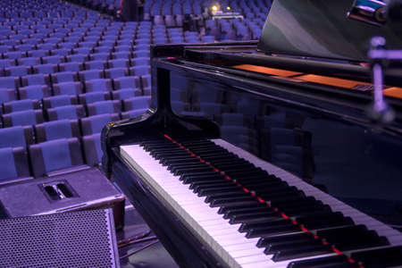 A black classic grand piano stands on stage. classical musical instrument close upの写真素材