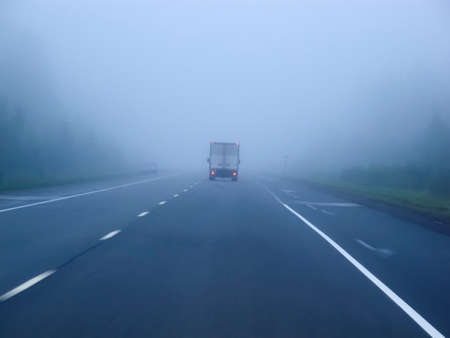Cars in the fog. Bad weather and dangerous automobile traffic on the road. Light vehicles in fog.の写真素材